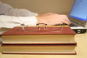 photo of books and a person typing on a computer